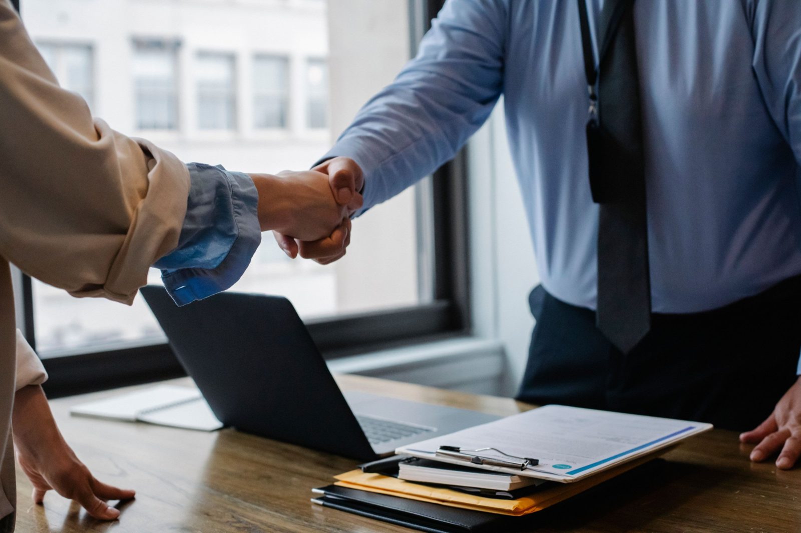 Two people shaking hands across a desk
