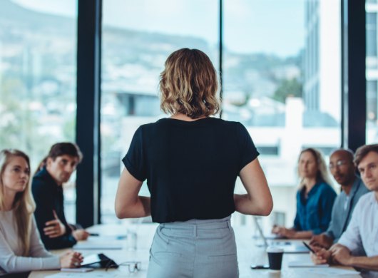 A team listening to a colleague in a meeting room