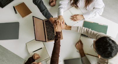 Team members joining hands over a table